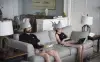 Man and a woman sitting on a couch with their laptops. They have shark hats on their heads.
